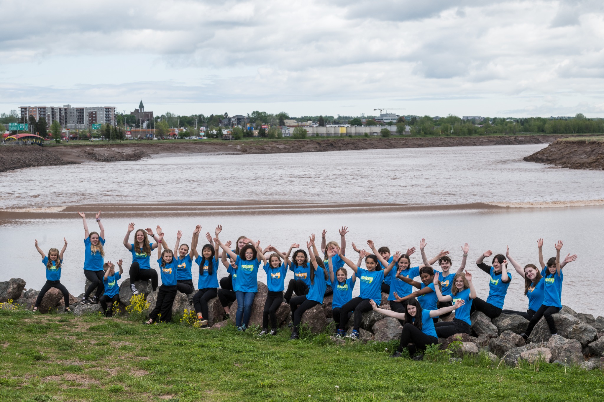 Voices Rising singers celebrating together beside the Petitcodiac River